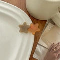 Close-up of star-shaped acetate hair clips in khaki and amber colors on a ceramic plate - Orange Star/BTS Style