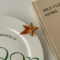 Detail of an amber acetate star-shaped hair clip with tortoise shell pattern on a plate - Amber