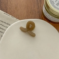 Detailaufnahme einer bernsteinfarbenen Mini-Haarklammer mit goldenem Schriftzug - Braun