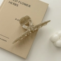 Detailed macro view of large acetate claw clip with cream marble texture on a book - Beige Coffee