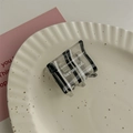 Detailansicht einer schwarz-weiß gestreiften Haarklammer mit Text auf einem Keramiktablett - Schwarz Kleiner Quadratischer Greifer