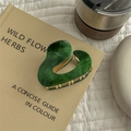 Detail of green marble acetate hair claw with gold metal teeth on a vintage book - Green