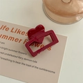 Vista dettagliata di una clip per capelli quadrata bordeaux con motivo a cuore su beige - Rosso Scuro