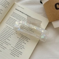 Nahaufnahme der irisierenden perlweißen Haarklammer auf einem Buch bei sanftem Licht - Irisierendes Weiß