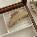 Detalle de la pinza para el pelo caqui con texto dorado Barrette La France sobre madera - Caqui