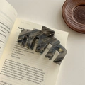 Makro-Detail einer edlen Acetat-Haarklammer mit Marmormuster auf antikem Buch - Premium Grau