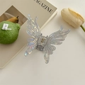 Gros plan sur la pince à cheveux papillon avec fini perlé irisé et design ajouré - Pince Papillon Grise Colorée