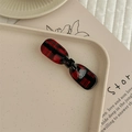Detailaufnahme einer rot-schwarz karierten Acetate-Haarklammer mit Schleife auf Tablett - Schwarz-Rot Kariert