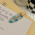 Détail d'une barrette en résine avec paillettes étoiles bleues sur carte décorative - Bleu transparent
