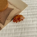 Dettaglio di un grande fermaglio per capelli a forma di croissant con texture dorata su tessuto - Forma Croissant Piccola