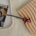 Detailed macro view of vintage red ribbon bow hair clip with golden letters on metal base - Red