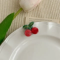 Gros plan d'une jolie pince à cheveux cerise rouge en acétate sur une assiette blanche - Cerise