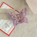 Détail d'une pince à cheveux papillon en résine marbrée violette avec ressort en métal doré - Lavande