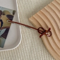 Detailed macro view of vintage resin bow hair clip with silver metal bar and logo - Brown