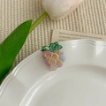 Détail d'une pince à cheveux raisin violet sur assiette en céramique avec une tulipe - Raisins