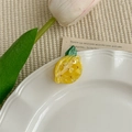 Détail d'une pince à cheveux citron avec texture marbrée jaune et feuille verte sur l'assiette - Citron