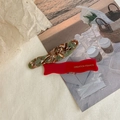 Detailweergave van golvende haarspelden in rood en marmergroen met gouden letters - Rood en Groen Patroon