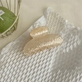 Dettaglio di un fermaglio per capelli in acetato crema su sfondo bianco a nido d'ape - Unico Giallo