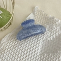 Dettaglio molletta per capelli in acetato marmorizzato blu su sfondo di carta bianca - Unico Blu