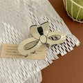 Detail einer cremefarbenen Schleifen-Haarklammer mit schwarzen Rändern auf Hintergrund - Schleife Haarkralle - Beige