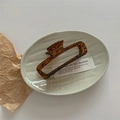 Detalle de la elegante pinza para el cabello de ámbar con patrón carey en un plato gris - Patrón Marrón Caramelo