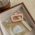 Detailed close-up of a square pink marble acetate hair claw clip with golden metal frame - Pink