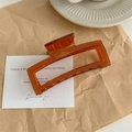 Primer plano de la pinza para el pelo ámbar con logotipo France Handmade sobre papel - Café Gelatina