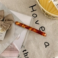Macro detail of tortoiseshell acetate hair clip with warm amber pattern on fabric background - Gradient Coffee