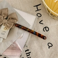 Close-up of tortoise shell pattern hair clip on transparent box with warm lighting - Lake Blue Coffee
