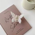 Pink butterfly hair claw clip with pearlescent acetate finish on a book - Iridescent White