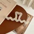 Detailed macro view of an oversized wavy hair claw clip with a pearlescent heart design - Iridescent Yellow