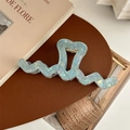 Macro detail of a large heart-shaped wavy hair claw clip in iridescent light blue color - Iridescent Blue Green