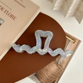 Close-up of light blue pearlescent oversized wave hair claw with heart design - Iridescent Blue Gray