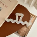 Close-up of heart-shaped iridescent pearl hair claw clip with wave design on a minimalist background - Iridescent White