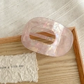 Macro shot of an elegant pink marble acetate hair claw clip on a light wooden tray - Metallic Pink