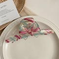 Dettaglio del fermaglio a fiocco in acetato a righe rosa e blu con logo dorato - Striscia Blu Rosa
