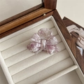 Detailed macro view of purple marble acetate bow hair claw clip on white velvet - Pink and White Floral