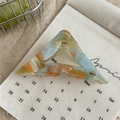 Détail de la pince à cheveux triangle en acétate marbré avec finitions dorées sur toile - Arc-en-ciel