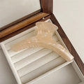 Detailed close-up of a large champagne pearlescent hair claw clip in a velvet jewelry box - Phantom Yellow