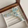 Close-up of handmade large acetate hair claw clip with light wood marble pattern - Blue and Yellow Floral