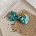 Makroaufnahme der marmorierten Haarklammer mit Strassbesatz und goldenem YD-Logo-Detail - Monet Blau