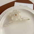 Detailaufnahme der perlmuttartigen Acetat-Blumenhaarklammer mit kleinem Gänseblümchen-Akzent - Perlmuttweiß
