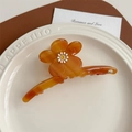 Makroaufnahme der bernsteinfarbenen Blumen-Haarklammer mit Gänseblümchen-Detail - Orange Streifen