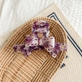 Detailed view of a purple marble bow claw clip with handmade gold tag on a woven tray - Purple