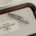 Macro detail of tortoiseshell acetate barrette with golden French lettering on wooden tray - Black Polka Dot