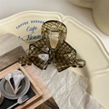 Detail of coffee resin bow hair claw clip with checkered pattern on a cream tray - Ancient Lace