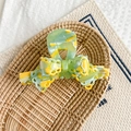 Detail showing the green and yellow marble texture bow hair claw with handmade logo - Yellow-Green