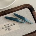 Detailed top view of dark green acetate hair clip with gold logo on a wooden tray - Green (With Card)