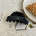 Detail of elegant black acetate hair claw with gold logo on French style magazine background - Black