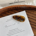 Detailansicht der bernsteinfarbenen Acetats-Haarklammer mit goldener handgefertigter Schrift - Seeblau Kaffee
